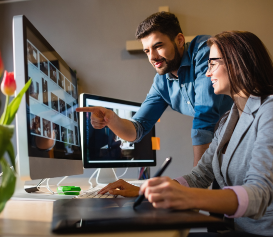 One male and one female designer reviewing design mockups in a desktop screen at an office space.