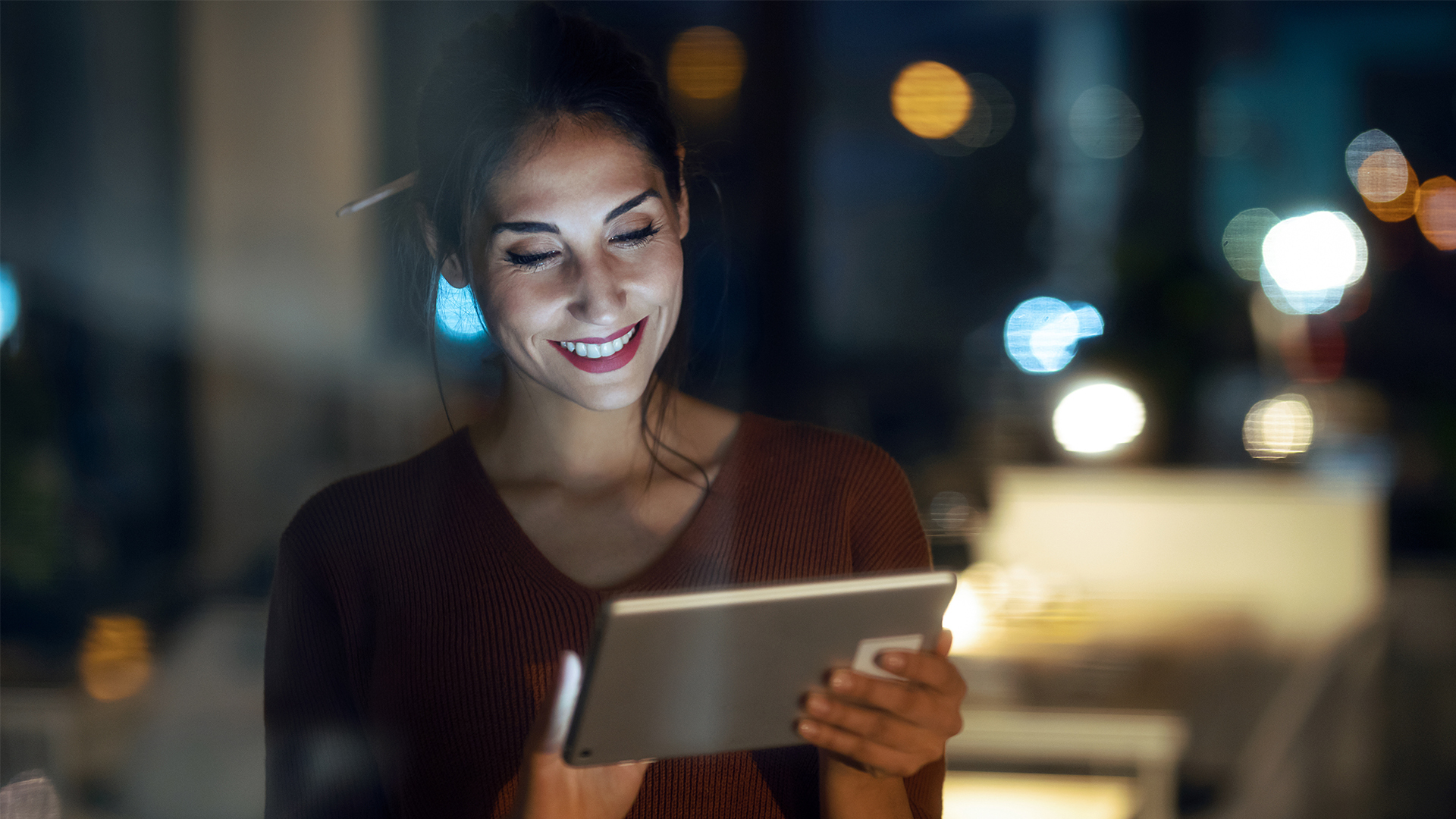 A woman smiles while engaging with a tablet computer, showcasing a moment of joy and technology in use