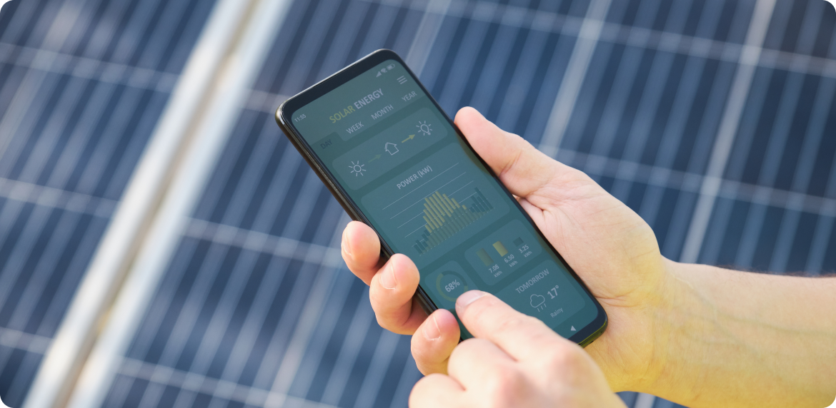 A male worker reviewing solar energy data and consumption over a smartphone with a solar panel background