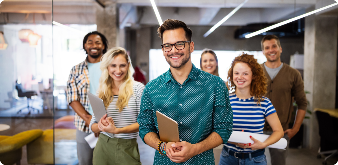 Multiple finance workers smiling and holding a computer in their hands at an office