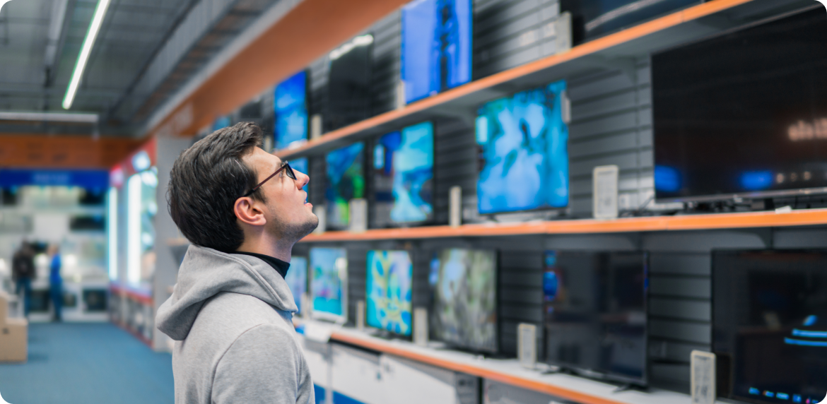 A male customer at a retail store looking for products in a store wall