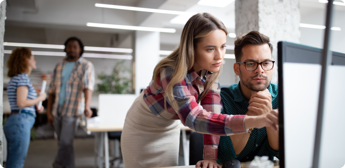 Multiple real estate agents analyzing industry trends over a computer monitor at the office.