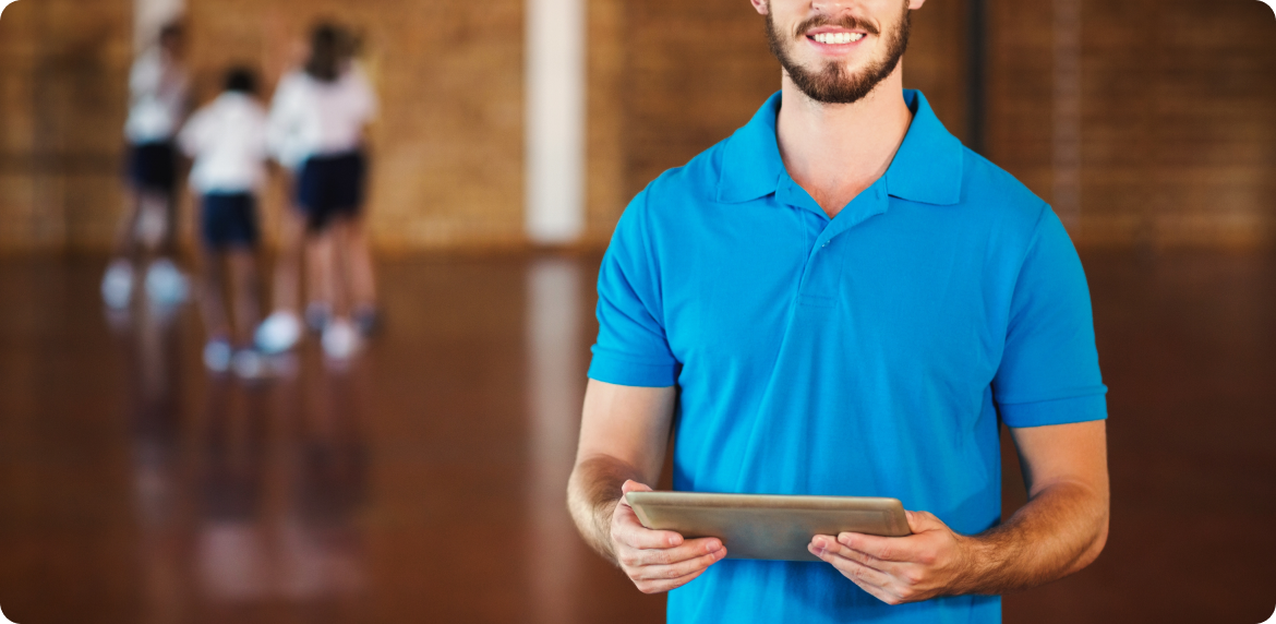 Male real estate agent smiling and holding a tablet in his hands while being in a house for sale