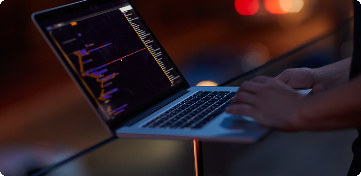 A worker's hands in a laptop manipulating code at night