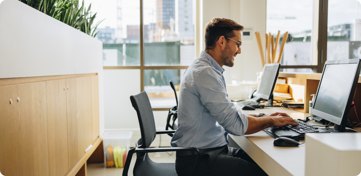 Smiling male businessmen in a blue shirt typing in an office setting