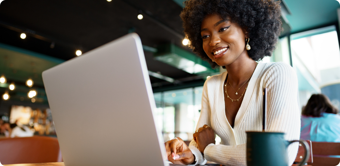 Smiling businesswoman starting at a computer in a coffee shop